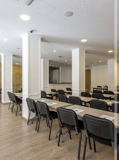 Conference centre set classroom-style with long tables and black chairs