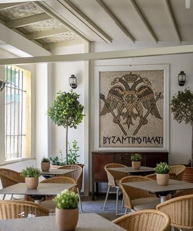 Byzantino Palati courtyard dining room with a Byzantine eagle mosaic and wicker chairs